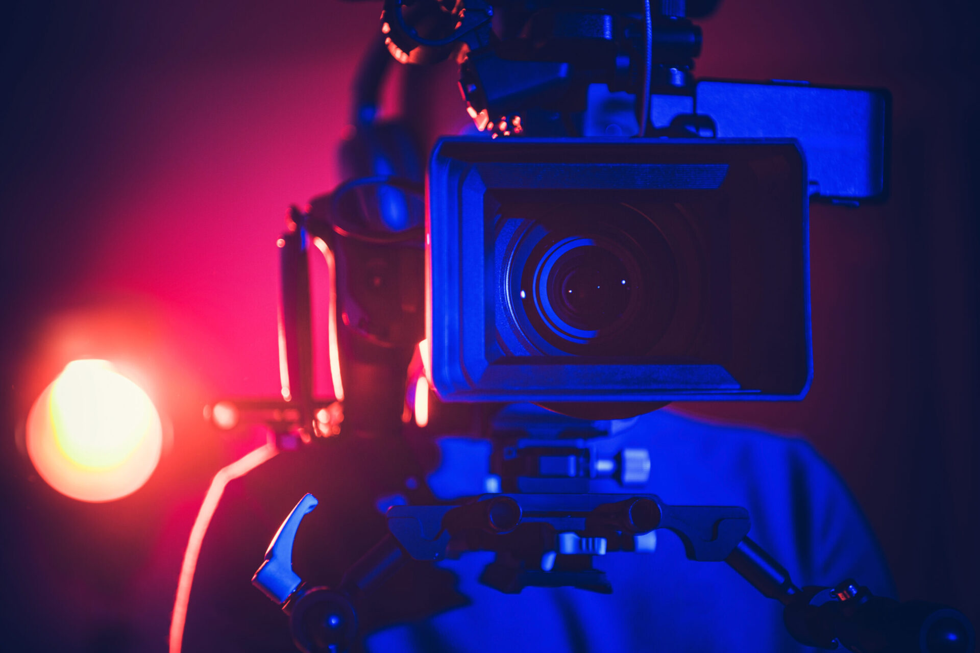 A Filmmaker Operates a Professional Camera Under Vibrant Colored Lights in a Studio Setting